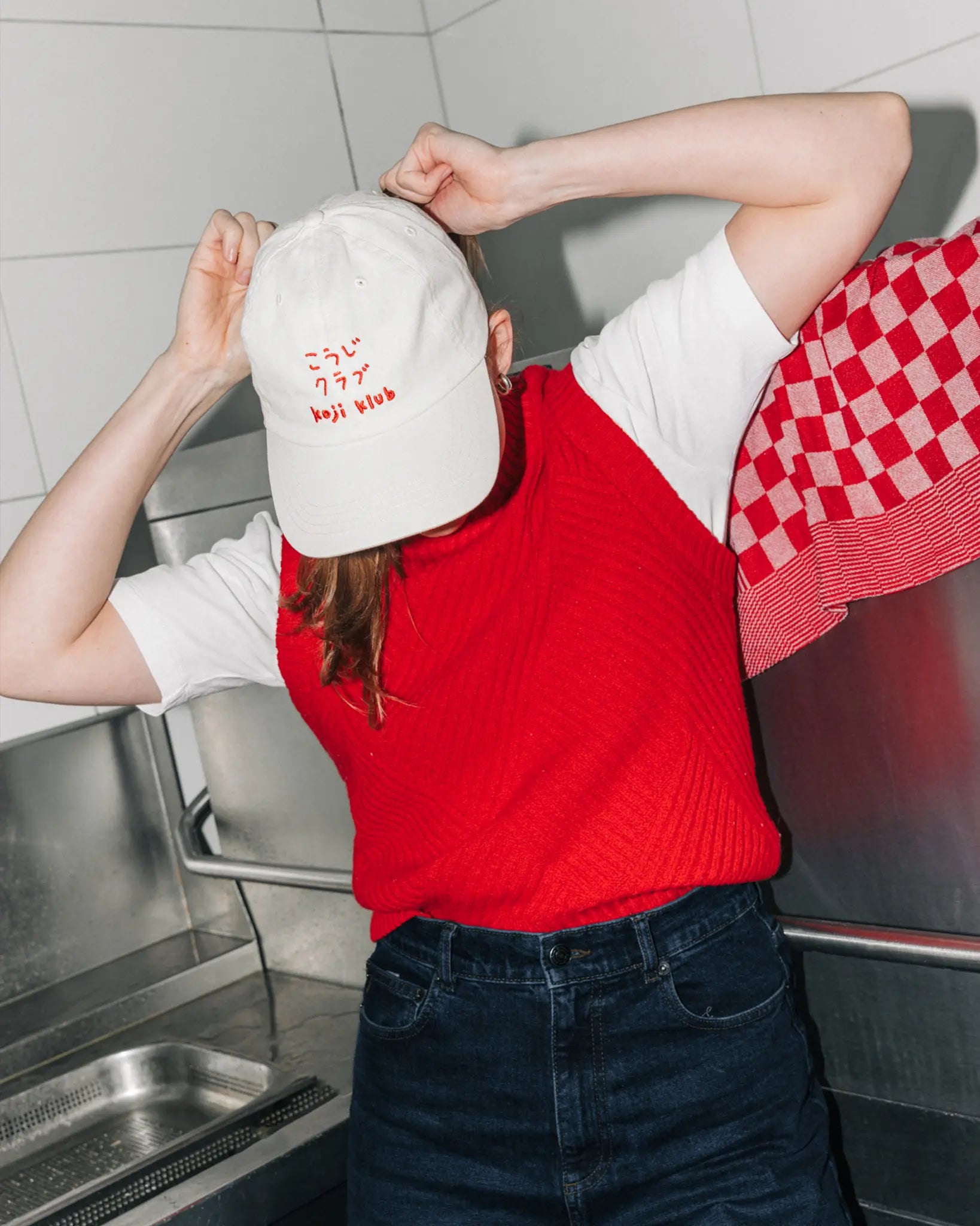 Miso Miso Team traegt weiße Koji Klub Cap mit rotem Stick-Logo in der Kueche.