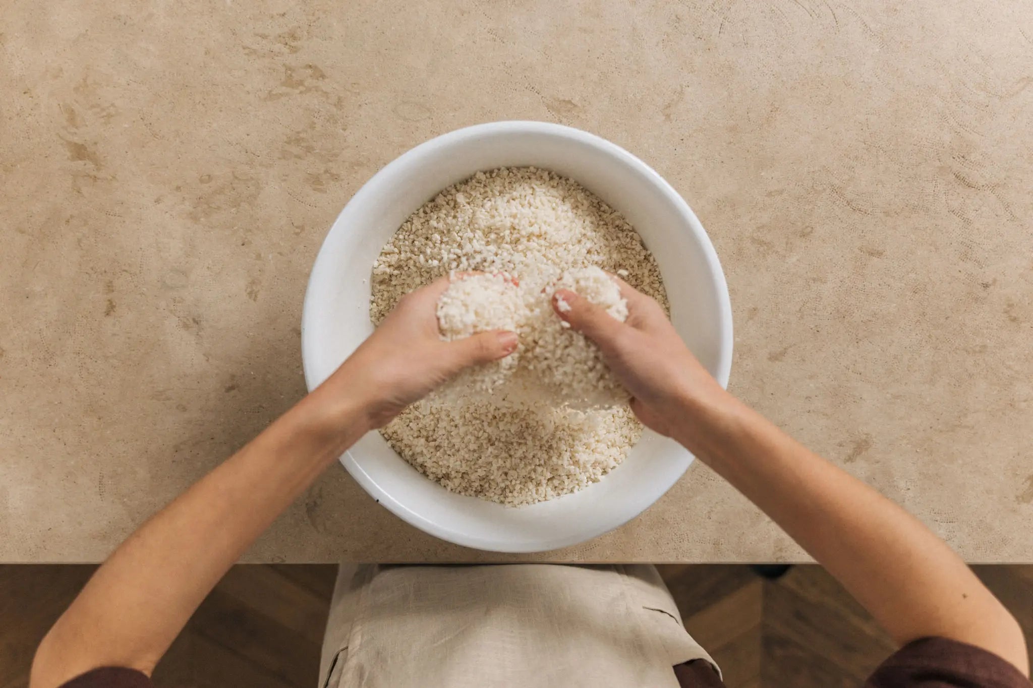 hände lockern weiß fermentierten koji-reis in einer schüssel auf. traditionelle koji-herstellung für unpasteurisiertes miso miso aus heidelberg.